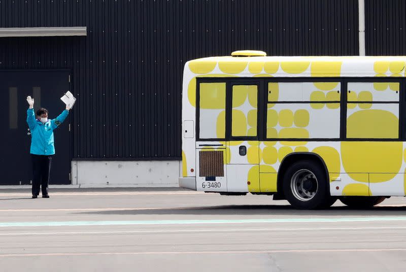 A man waves as a bus believed to be carrying some passengers from the cruise ship Diamond Princess, leaves at Daikoku Pier Cruise Terminal in Yokohama, south of Tokyo