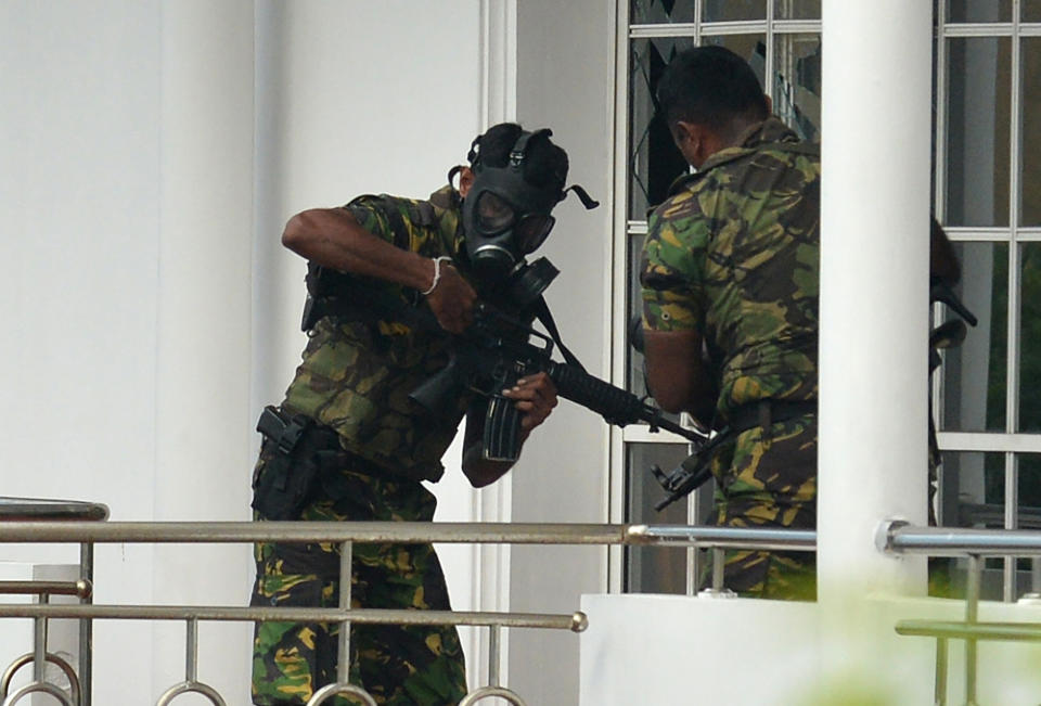 Sri Lankan Special Task Forcepersonnel in gas masks are pictured outside a house during a raid after a suicide blast had killed police searching the property in the Orugodawatta area of the capital Colombo on Sunday. Source: Getty Images