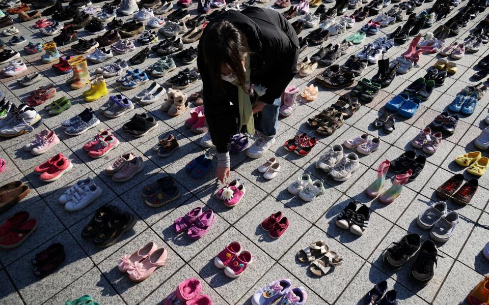 An activist places a floral tribute on a pair of baby shoes symbolising Palestinians killed in Seoul, South Korea