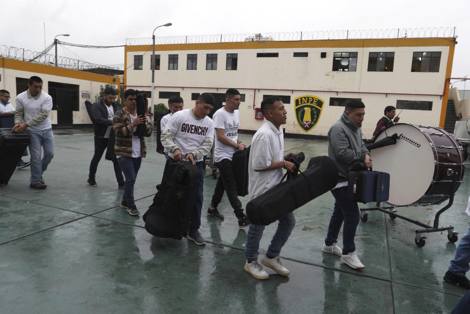 In this July 19, 2019 photo, handcuffed inmates, instruments in tow, walk to an armored bus that will transport them to a classical music rehearsal as part of a pioneering project to rehabilitate criminals, at the prison in Callao, Peru. The goal is to create a prison symphony in time for when Peru celebrates its bicentennial in 2021. The inmates have already learned to play the theme from “Game of Thrones” and pieces by Beethoven. (AP Photo/Martin Mejia)