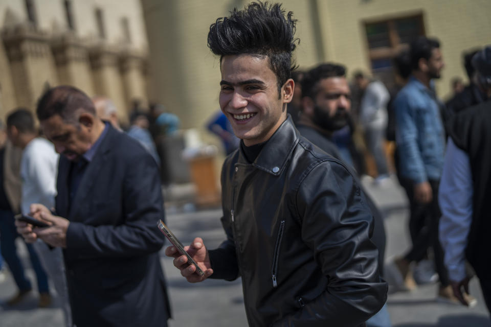 A man holds his cellphone near Al-Mutanabbi street in Baghdad, Iraq, Friday, Feb. 24, 2023. Two decades after a U.S.-led invasion, Iraq’s capital today is full of life and a sense of renewal, its residents enjoying a hopeful, peaceful interlude in a painful modern history. (AP Photo/Jerome Delay)