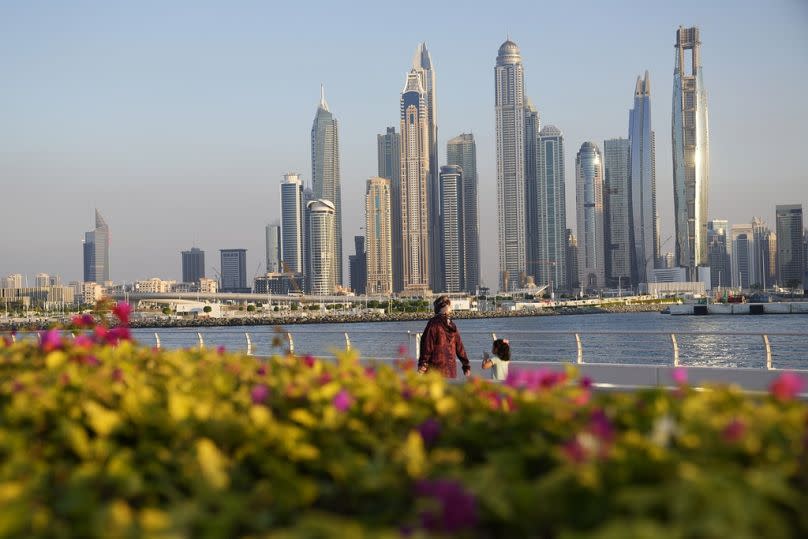 People walk with the skyline in the background as Dubai, United Arab Emirates, hosts the COP28 U.N. Climate Summit, Tuesday, Dec. 5, 2023.