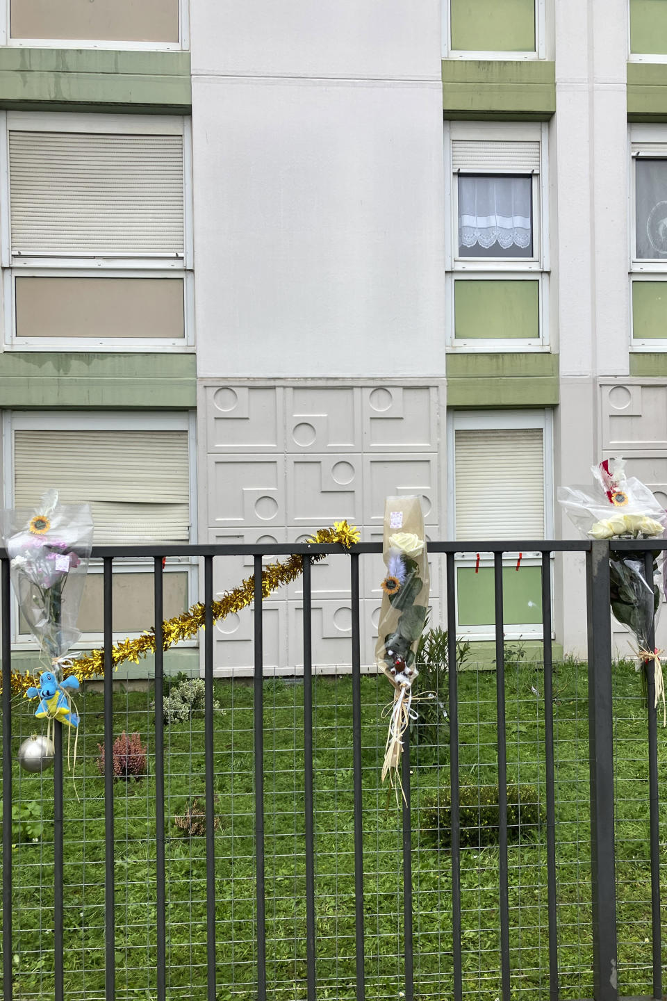 Flowers lay at the building gate after four children between nine months and 10 years old and their mother were found killed, Tuesday, Dec.26, 2023 in Meaux, east of Paris. A woman and her four children, between nine months and 10 years old, were killed in their apartment east of Paris in what the local prosecutor called an exceptionally violent crime. Authorities said the children's father was arrested Tuesday and is the primary suspect. (AP Photo/Nicolas Garriga)