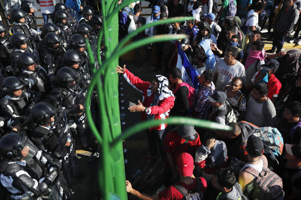 Migrantes discuten con los efectivos de la Guardia Nacional mexicana en el cruce fronterizo entre Guatemala y México en Tecún Umán, Guatemala, sábado 18 de enero de 2020. (AP Foto/Marco Ugarte).