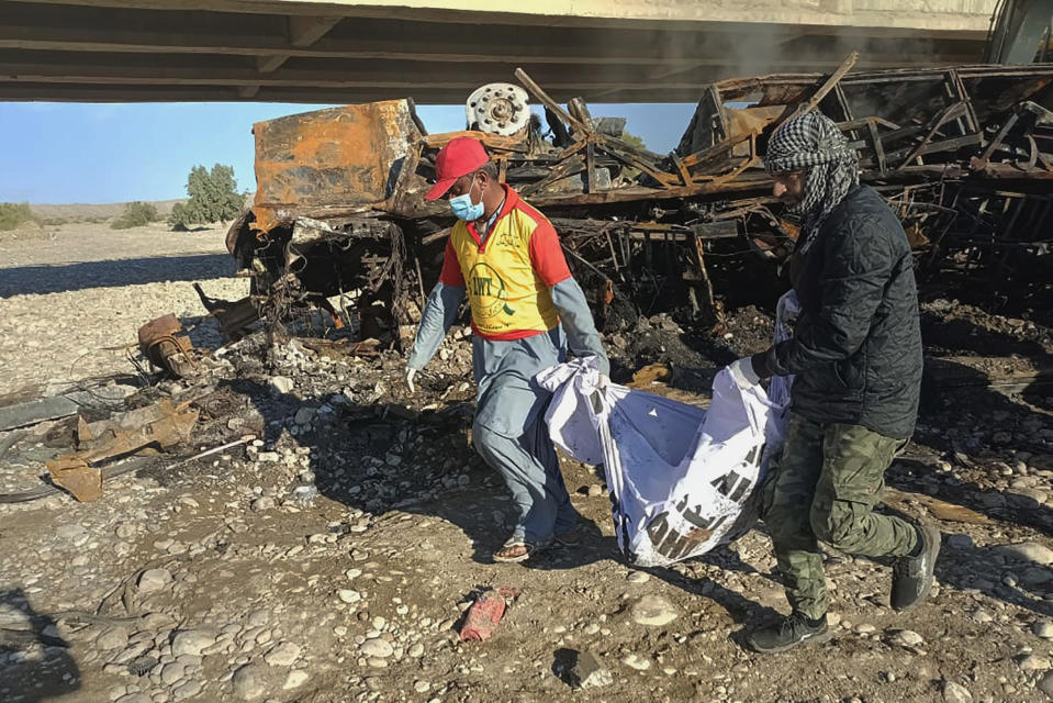 Rescue workers collect remains from the burnt wreckage of a bus accident in Bela, an area of Lasbela district of Balochistan province, Pakistan, Sunday, Jan. 29, 2023. The passenger bus fell into a ravine and caught fire killing dozens people in southern Pakistan on Sunday, a government official said. (AP Photo)