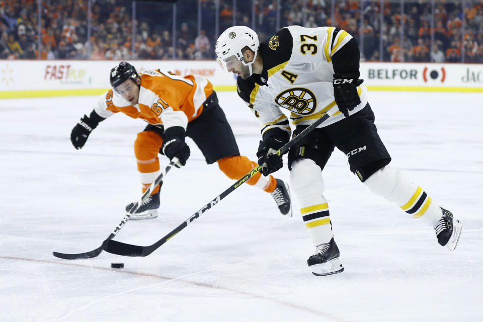 Boston Bruins' Patrice Bergeron (37) tries to skate past Philadelphia Flyers' Justin Braun (61) during the first period of an NHL hockey game, Tuesday, March 10, 2020, in Philadelphia. (AP Photo/Matt Slocum)