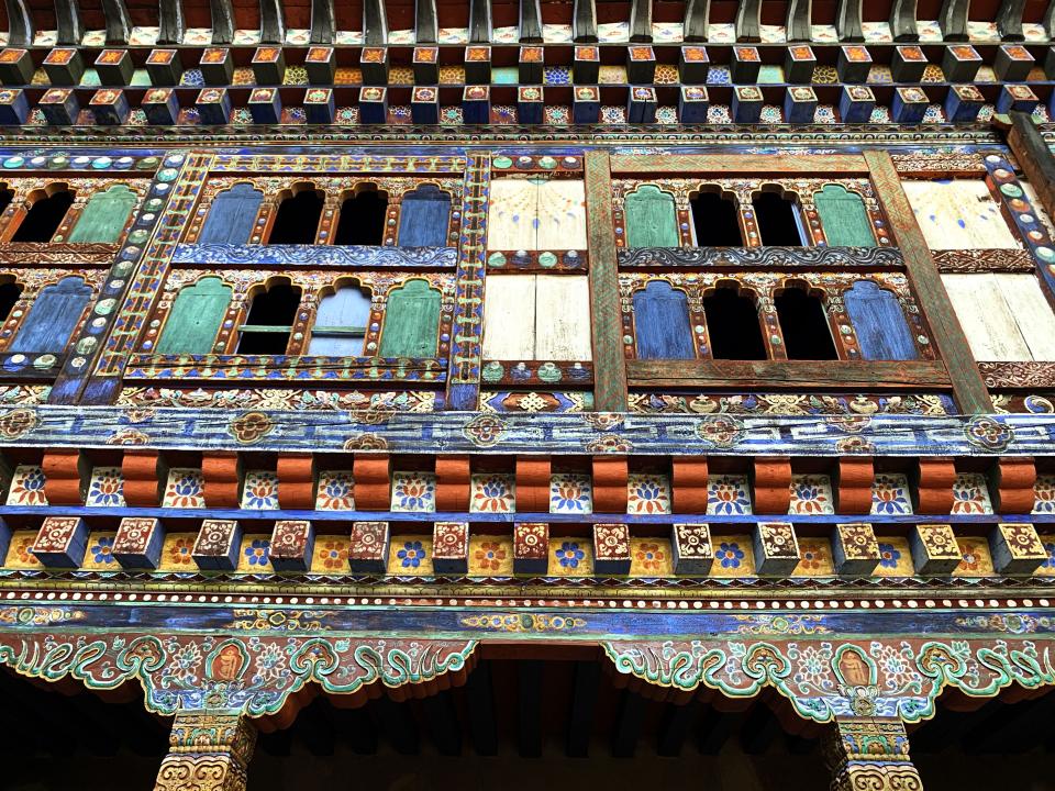 A view of the palace courtyard, showing the elaborately carved and polychromed wood façade, columns, and capitals.