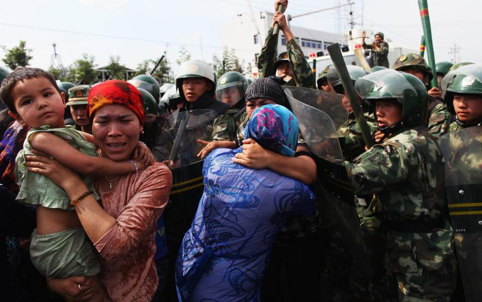 Women hold their children as they are pushed by police