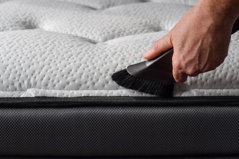 Closeup woman's hand using vacuum cleaner to vacuum matress