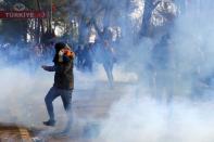 A migrant covers his face as tear gas floats in the air during clashes with Greek police, at the Turkey's Pazarkule border crossing with Greece's Kastanies, in Edirne