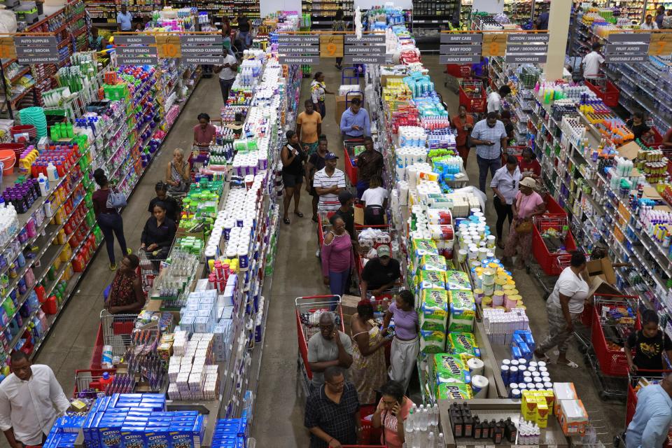 People wait in line with groceries ahead of the arrival of Hurricane Beryl, in Kingston, Jamaica, Monday.