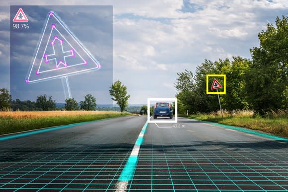 Front view from inside a driverless vehicle traveling on a two-lane road in a rural area, which shows a yellow square around a road sign and a white square around the car in front.