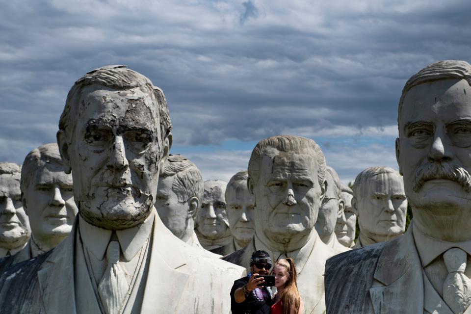 A couple poses for a selfie with giant salvaged busts of former US Presidents August 25, 2019, in Williamsburg, Virginia. (Photo: Brendan Smialowski/AFP/Getty Images)