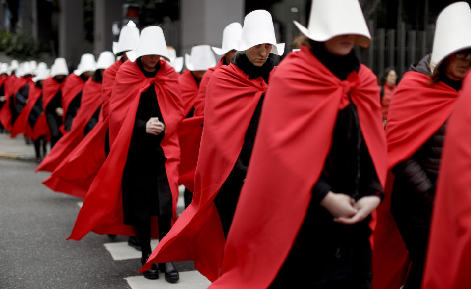 In this July 25, 2018 photo, women in favor of a measure to expand legal abortions, wearing red cloaks and white bonnets like the characters from the novel-turned-TV series "The Handmaid's Tale", march in silence to Congress, in Buenos Aires, Argentina. Once they reached Congress, one of them read a letter by "Handmaid's Tale" author Margaret Atwood, who supports the effort led by Argentine feminist groups. (AP Photo/Natacha Pisarenko)