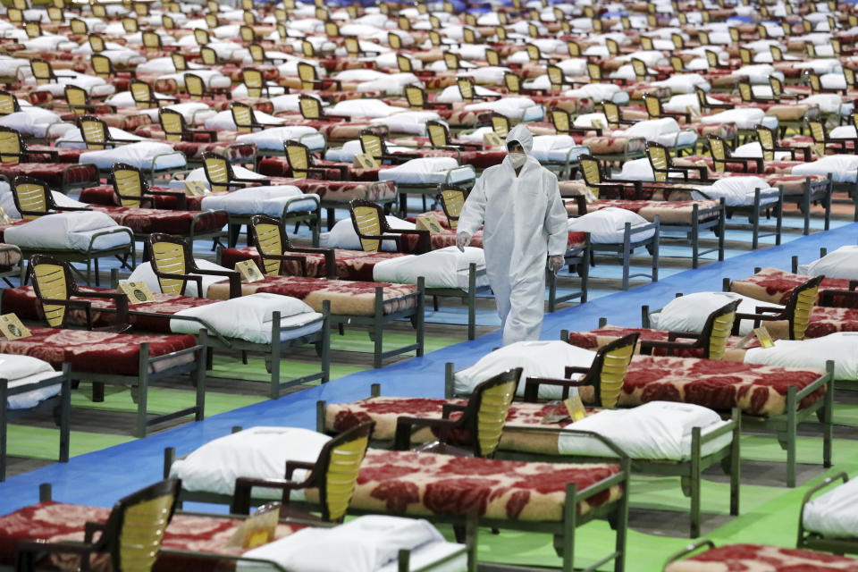 A person in protective clothing walks through a temporary 2,000-bed hospital for COVID-19 coronavirus patients set up by the Iranian army at the international exhibition center in northern Tehran, Iran, on Thursday, March 26, 2020. (AP Photo/Ebrahim Noroozi)