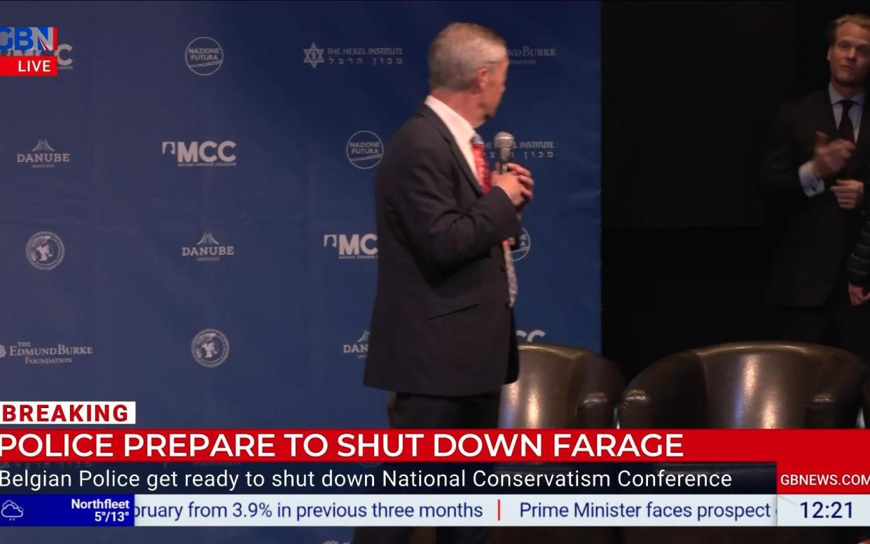 Nigel Farage appears to be beckoned off stage as he addresses the NatCon conference in Brussels