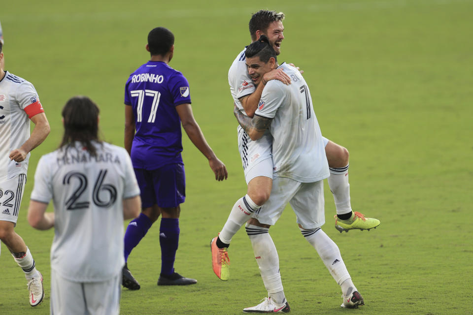 New England Revolution midfielder Kelyn Rowe (11) celebrates with forward Gustavo Bou (7) after an MLS playoff soccer match against Orlando City, Sunday, Nov. 29, 2020, in Orlando, Fla. (AP Photo/Matt Stamey)