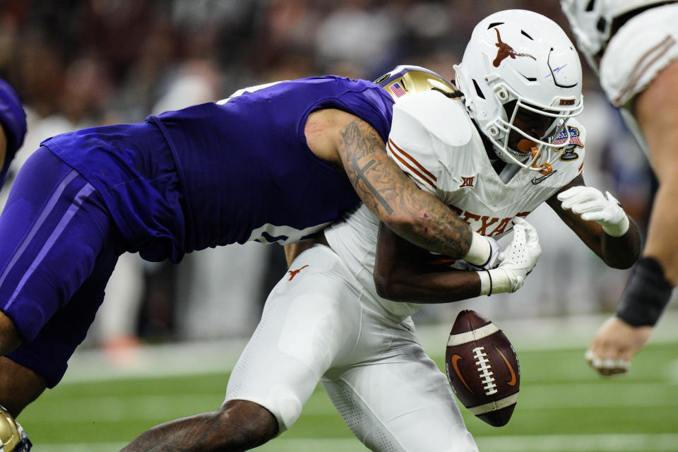 Washington defensive end Bralen Trice (8) hits the ball against Washington wide receiver Germie Bernard (4) causing a fumble during the second half of the Sugar Bowl CFP NCAA semifinal college football game, Monday, Jan. 1, 2024, in New Orleans. (AP Photo/Jacob Kupferman)