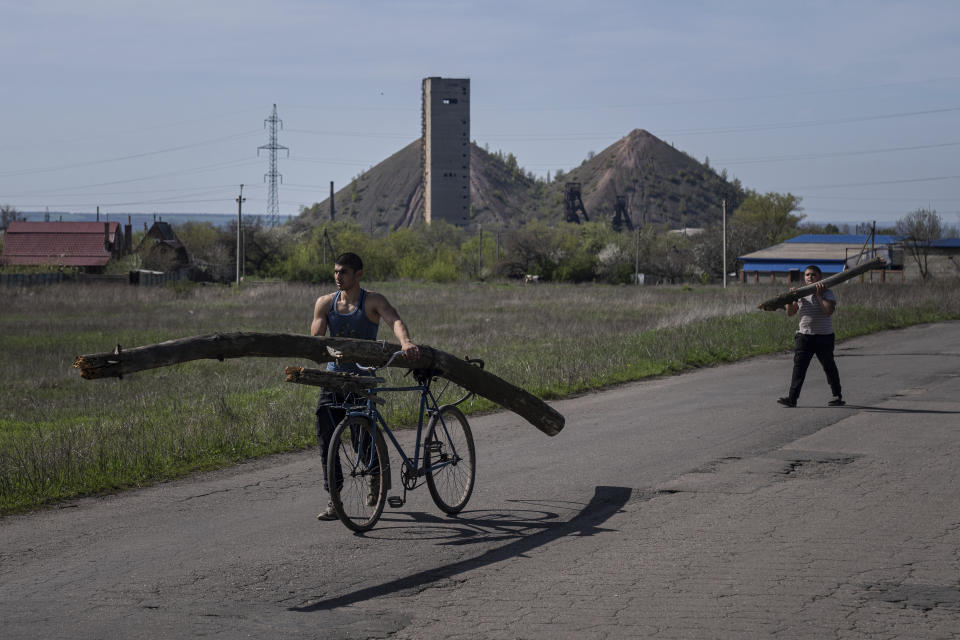 A man hauls a bicycle with a part of a tree branch in front of a coal mine in Toretsk, eastern Ukraine, Monday, April 25, 2022. (AP Photo/Evgeniy Maloletka)