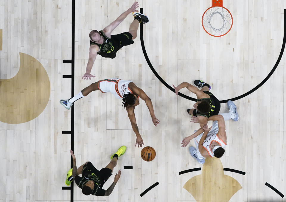 San Antonio Spurs guard Devin Vassell (24) passes between New Orleans Pelicans center Cody Zeller (40), guard Jordan Hawkins, bottom left, and guard Dyson Daniels (11) in the first half of an NBA basketball game in New Orleans, Friday, Dec. 1, 2023. (AP Photo/Gerald Herbert)