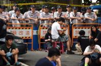 Policemen stand guard as protesters gather on a road near an entrance of the Education Ministry in Taipei on July 31, 2015