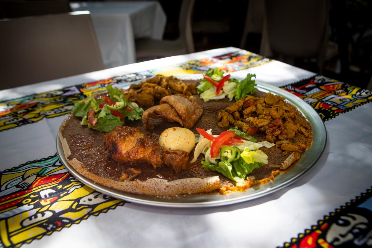 Doro Wat, bottom, beef tibs, top, sambussas, center, and lamb tibs top a piece of traditional injera bread at Zagwe’s Restaurant.