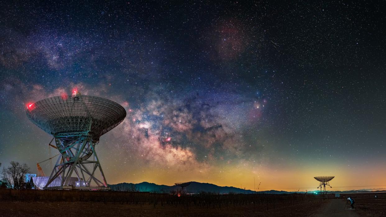  Radio telescopes point upwards under the milky way and stars. 