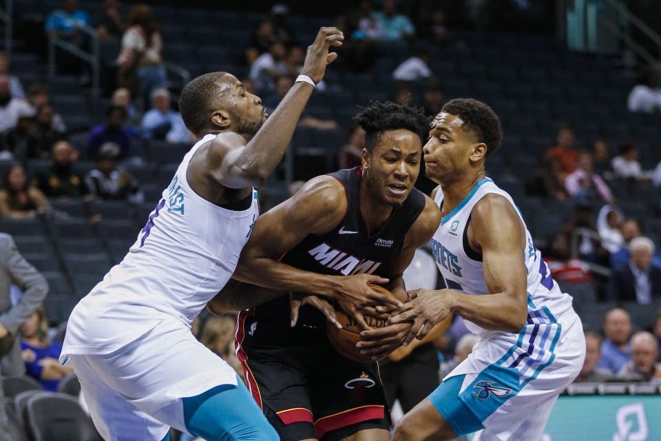 Miami Heat forward KZ Okpala, center, fights through a double-team by Charlotte Hornets forwards Michael Kidd-Gilchrist, left, and PJ Washington during the second half of an NBA preseason basketball game in Charlotte, N.C., Wednesday, Oct. 9, 2019. (AP Photo/Nell Redmond)