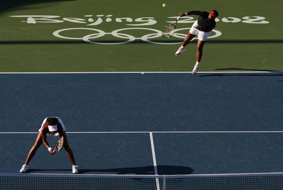 <p>Serena Williams of the United States serves as Venus Williams (left) looks on while taking on Ayumi Morita and Ai Sugiyama of Japan during the women’s doubles second round tennis at the Olympic Green Tennis Center on Day 7 of the Beijing 2008 Olympic Games on August 15, 2008 in Beijing, China. (Photo by Nick Laham/Getty Images) </p>