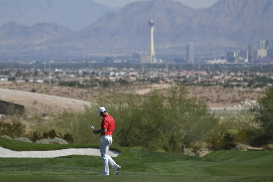 Rory McIlroy, of Northern Ireland, checks his notes as prepares for a shot on the third hole during final round of the CJ Cup golf tournament, Sunday, Oct. 17, 2021, in Las Vegas. (AP Photo/David Becker)