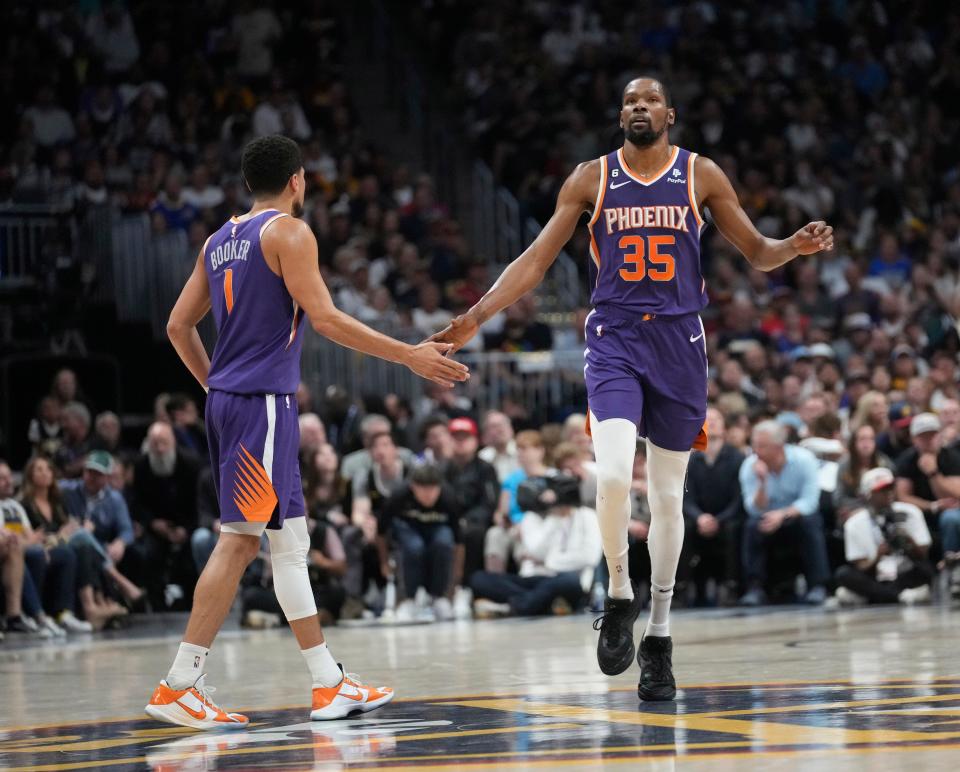 Phoenix Suns guard Devin Booker (1) and forward Kevin Durant (35) slap hands during the second quarter against the Denver Nuggets of the Western Conference semifinals at Ball Arena in Denver on May 9, 2023.