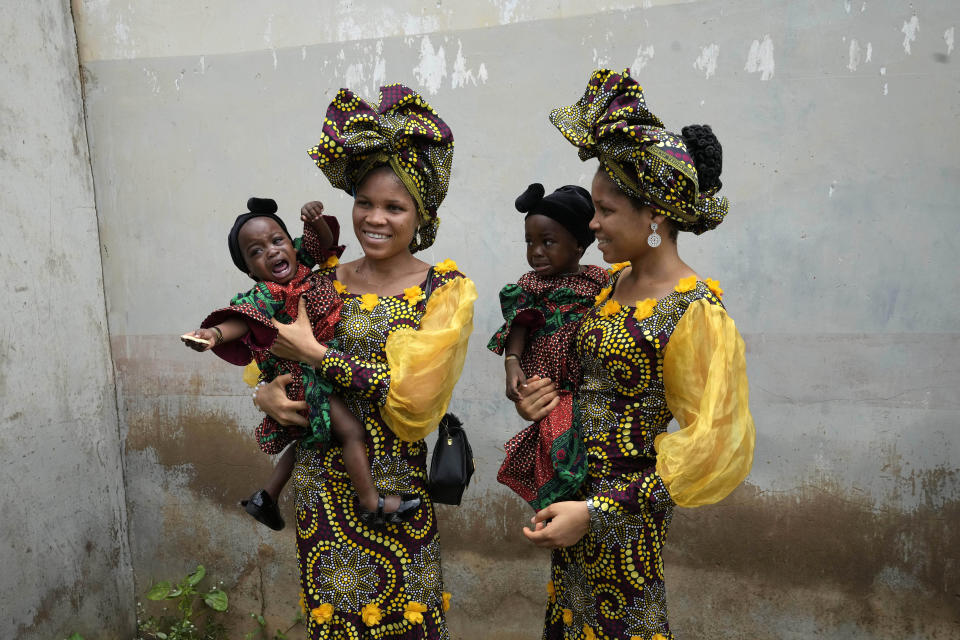 Twins Oladapo Taiwo, left, and Oladapo Kehinde, 21, pose for photographs holding relative's twins during the Annual twin festival in Igbo-Ora South west Nigeria, Saturday, Oct. 8, 2022. The town holds the annual festival to celebrate the high number of twins and multiple births. (AP Photo/Sunday Alamba)