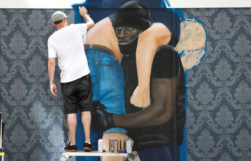 FILE PHOTO: Street artist Lionel Stanhope paints a mural depicting an image taken during a recent Black Lives Matter demonstration, on a hoarding near Lewisham station in London
