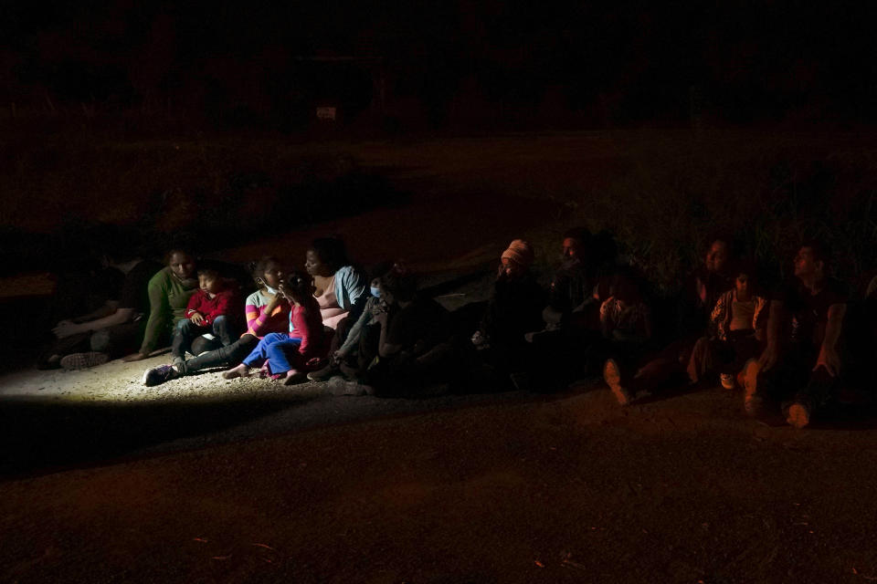 Varios migrantes, principalmente de Honduras y Nicaragua, hacen fila sentados después de entregarse al cruzar la frontera entre Estados Unidos y México, en esta fotografía de archivo del lunes 17 de mayo de 2021 en La Joya, Texas. (AP Foto/Gregory Bull, archivo)