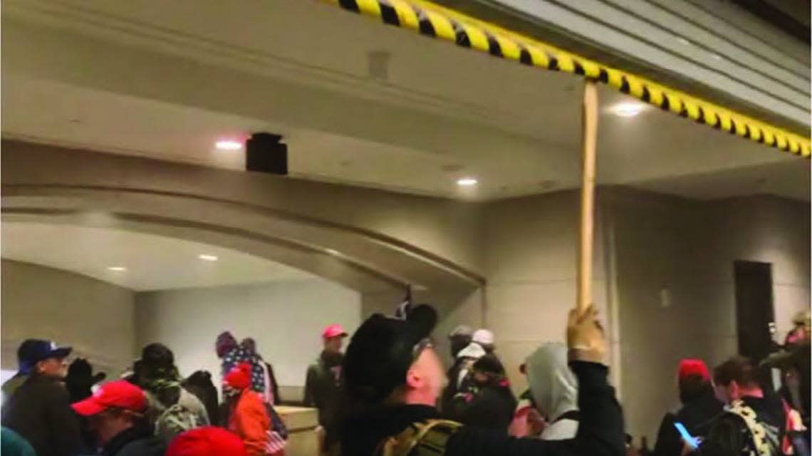 A man identified as William Chrestman of Olathe uses what was described as an ax handle to prevent a metal barrier from being lowered to keep the crowd back in the Capitol.