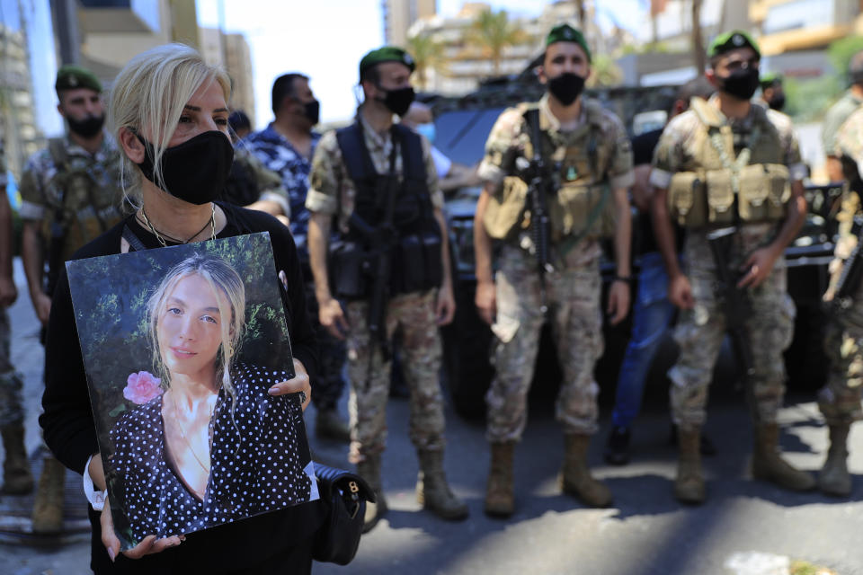 A woman holds a portrait of a victim who killed during the last year's massive blast at Beirut's seaport, protest near the tightly-secured residents of parliament speaker Nabih Berri, in Beirut, Lebanon, Friday, July 9, 2021. The protest came after last week's decision by the judge to pursue senior politicians and former and current security chiefs in the case, and requested permission for their prosecution. (AP Photo/Hussein Malla)