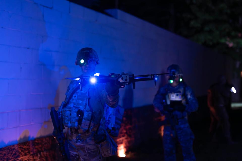 Man in combat gear holding X10 drone at night