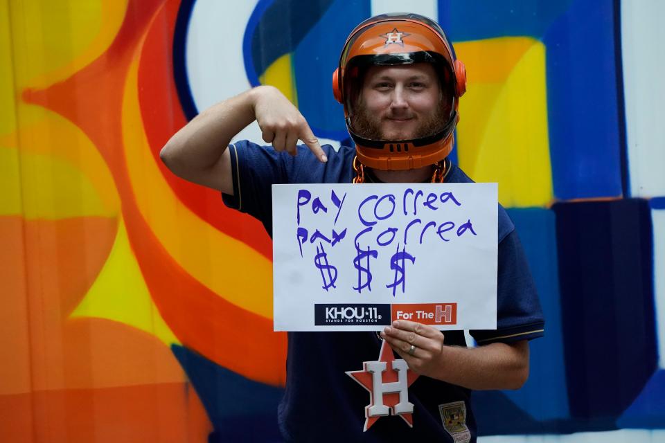 Astros fan Robert Rutherford holds a sign referring to shortstop Carlos Correa.