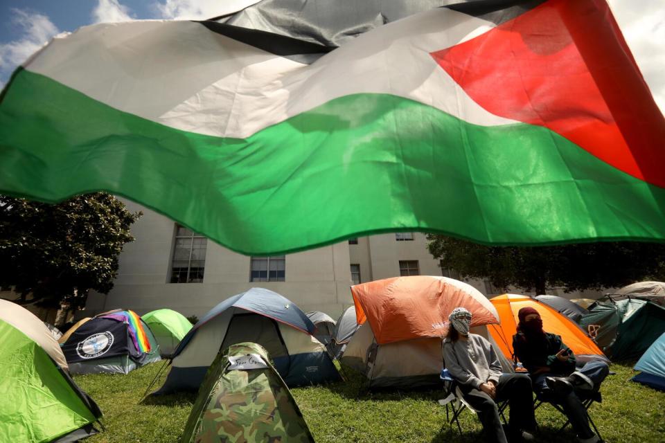 A Palestinian flag flies over tents at UC Berkeley.