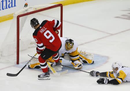 Nov 13, 2018; Newark, NJ, USA; New Jersey Devils left wing Taylor Hall (9) scores a goal against Pittsburgh Penguins goaltender Casey DeSmith (1) and defenseman Brian Dumoulin (8) during the third period at Prudential Center. Noah K. Murray-USA TODAY Sports