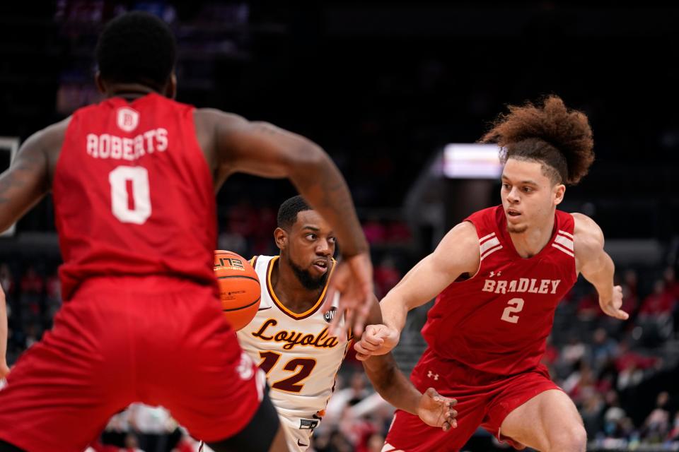 Loyola of Chicago's Marquise Kennedy (12) heads to the basket as Bradley's Terry Roberts (0) and Max Ekono (2) defend during the second half of an NCAA college basketball game in the quarterfinal round of the Missouri Valley Conference tournament Friday, March 4, 2022, in St. Louis. (AP Photo/Jeff Roberson)