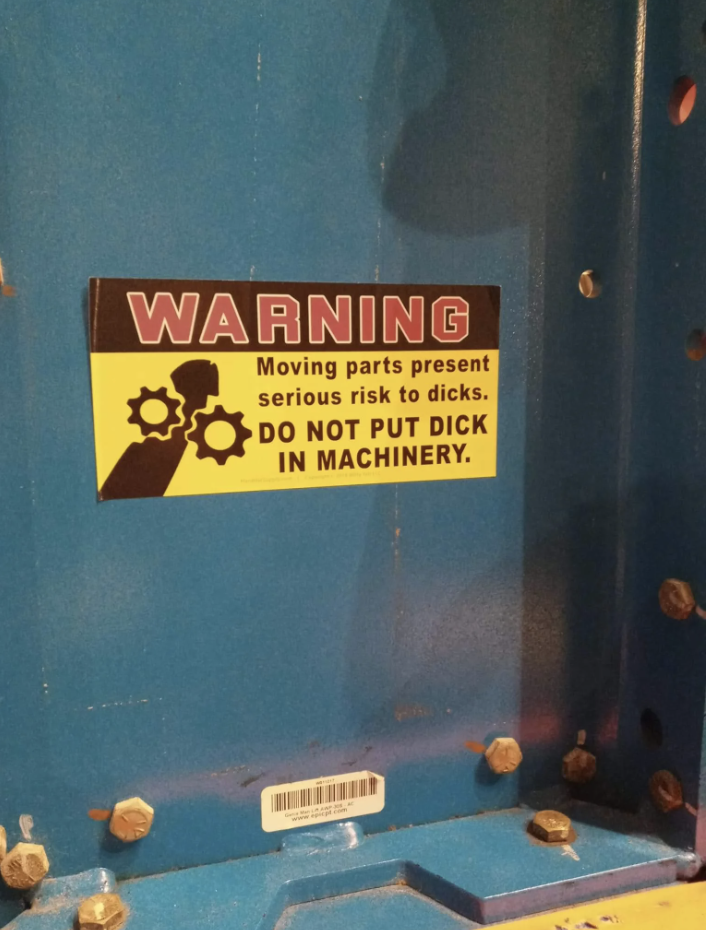 Warning label on machinery humorously cautioning against placing private parts inside