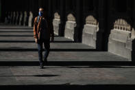 A man wearing a face mask walks through the colonnade of a government building in central Mexico City, Tuesday, March 24, 2020. Beginning Monday, Mexico's capital shut down museums, bars, gyms, churches, theaters, and other non-essential businesses that gather large numbers of people, in an attempt to slow the spread of the new coronavirus. (AP Photo/Rebecca Blackwell)