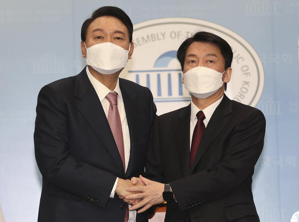 Presidential candidates Yoon Suk Yeol, left, of the main opposition People Power Party and Ahn Cheol-soo of the opposition People's Party shake hands after a joint press conference at the National Assembly in Seoul, South Korea, Thursday, March 3, 2022. South Korea's two main opposition presidential runners agreed Thursday to field a unified candidate of them, a last-minute political deal ahead of next week's vote that could boost prospects for an opposition win to restore a conservative rule. (Lee Jung-hoon/Yonhap via AP)