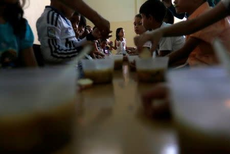 A student waits to be served as her classmates enjoy a soup cooked for them during an activity for the end of the school year at the Padre Jose Maria Velaz school in Caracas, Venezuela July 12, 2016. REUTERS/Carlos Jasso