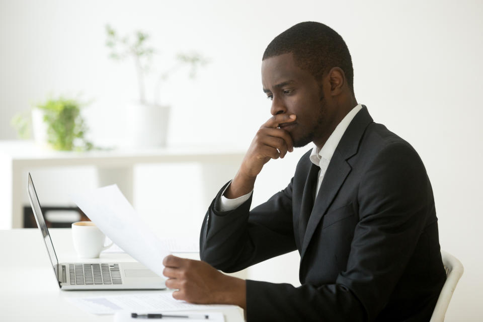 Young man in suit sitting at desk analyzing paperwork.