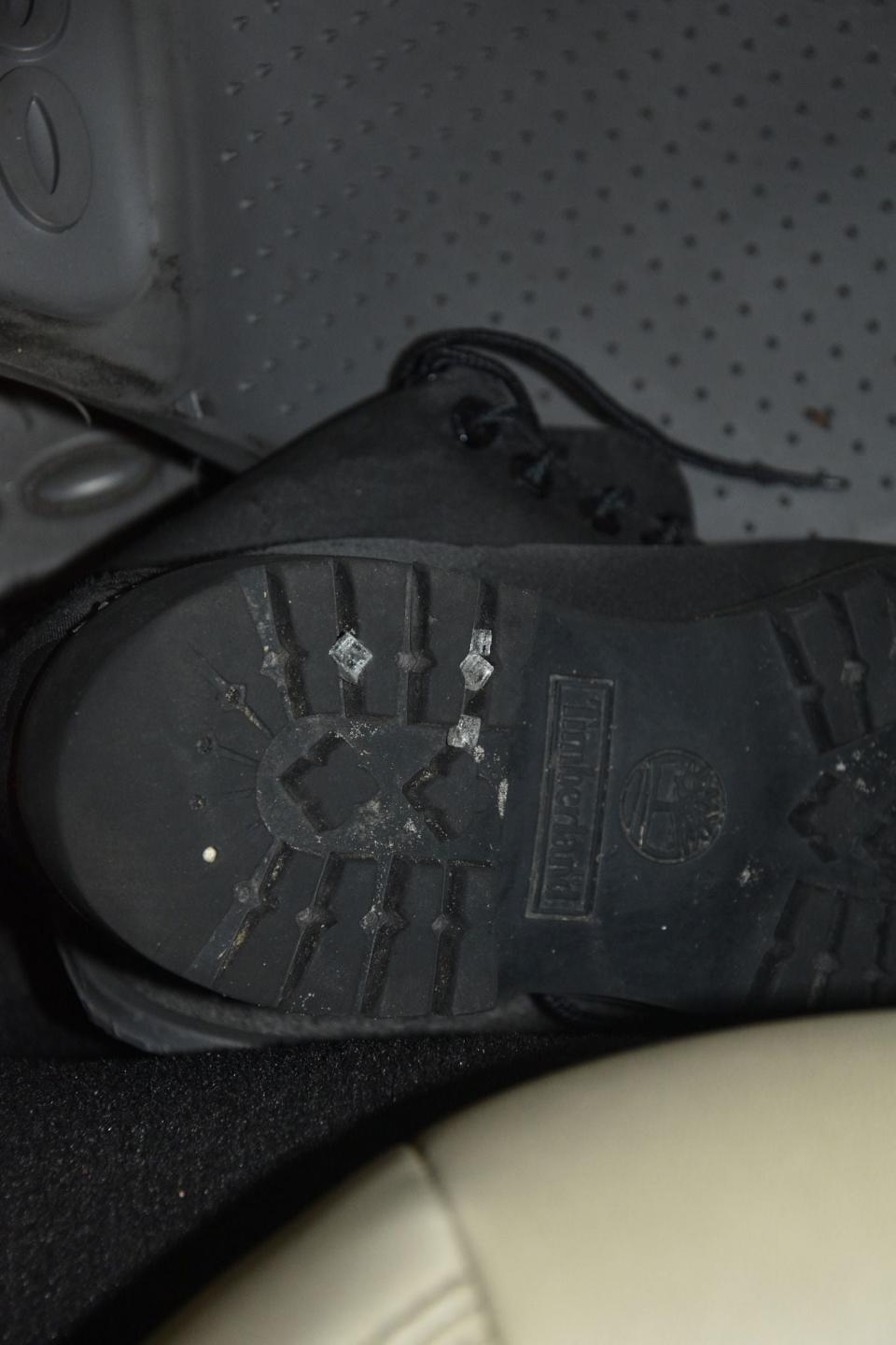 Black boots were found in the back seat of the suspect's car with shards of broken glass stuck in the soles.