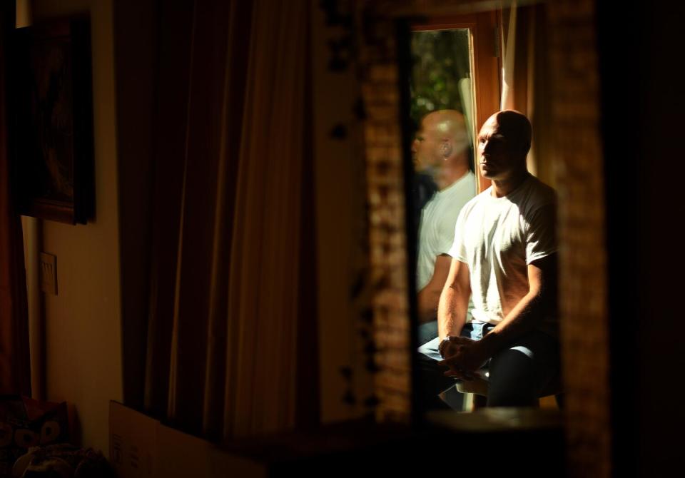 A man sits in a house at the window.