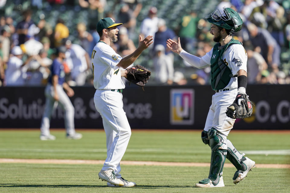 Oakland Athletics relief pitcher Austin Pruitt, left, and catcher Shea Langeliers celebrate the team's 5-3 victory against the Seattle Mariners in Oakland, Calif., Sunday, Aug. 21, 2022. (AP Photo/Godofredo A. Vásquez)