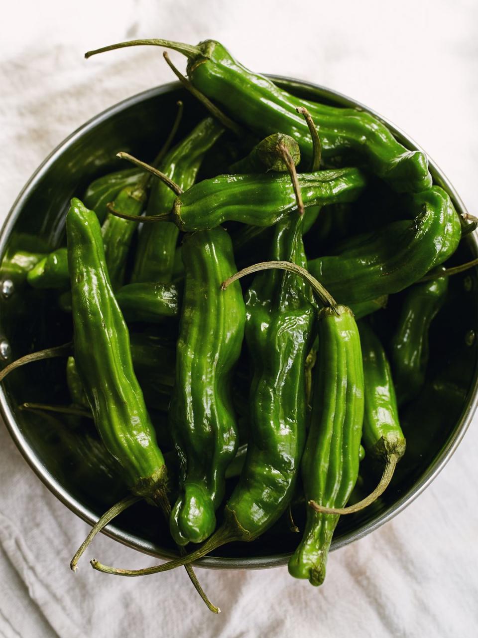 <p>You probably recognize these guys from restaurants, where they're often served grilled. "Shishito peppers are traditionally served in Japanese cuisine, roasted and tossed with sesame oil and a dash of soy sauce," Schueller said. "Choose peppers that are bright green with no red tinge." </p><p>They are super thin and easy to eat with almost no heat. The smoke or sear from a grill or pan adds a nice flavor to their mildness. Try this recipe for <a href="https://www.delish.com/cooking/recipe-ideas/a26988541/shishito-peppers-recipe/" rel="nofollow noopener" target="_blank" data-ylk="slk:blistered shishito peppers;elm:context_link;itc:0;sec:content-canvas" class="link ">blistered shishito peppers</a>. </p><p>Scoville heat units: 50-200</p>